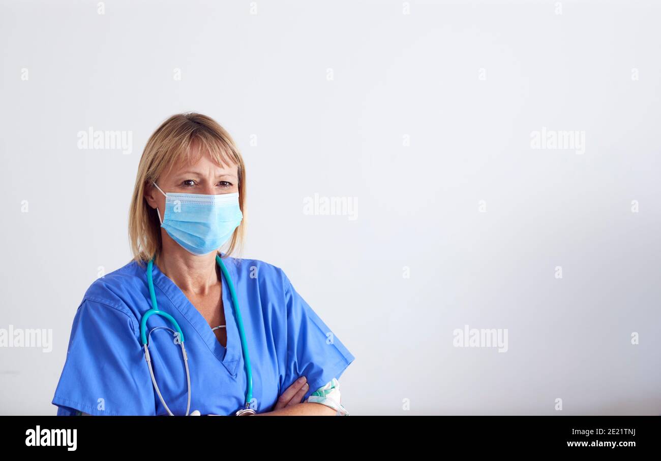 Studio Portrait Of Female Nurse Wearing Scrubs And PPE Face Mask And ...