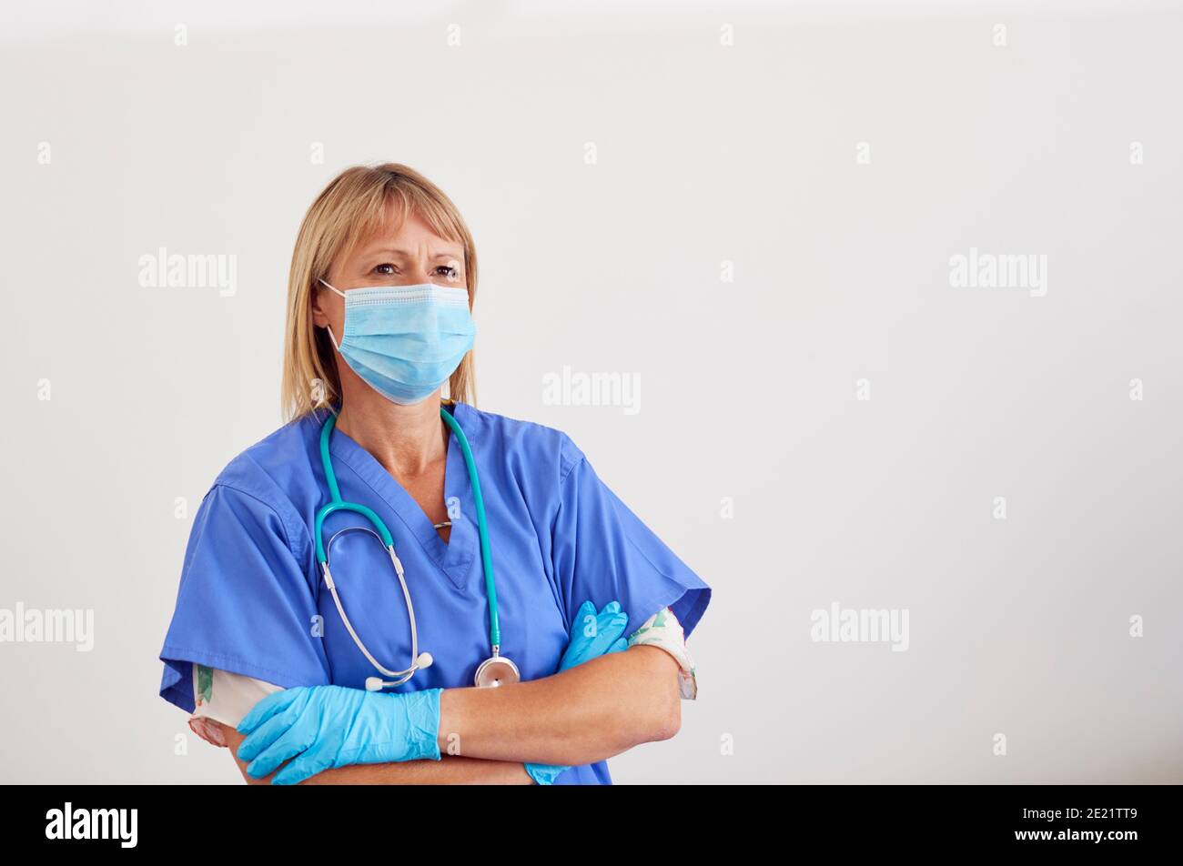 Studio Portrait Of Female Nurse Wearing Scrubs And PPE Face Mask And ...