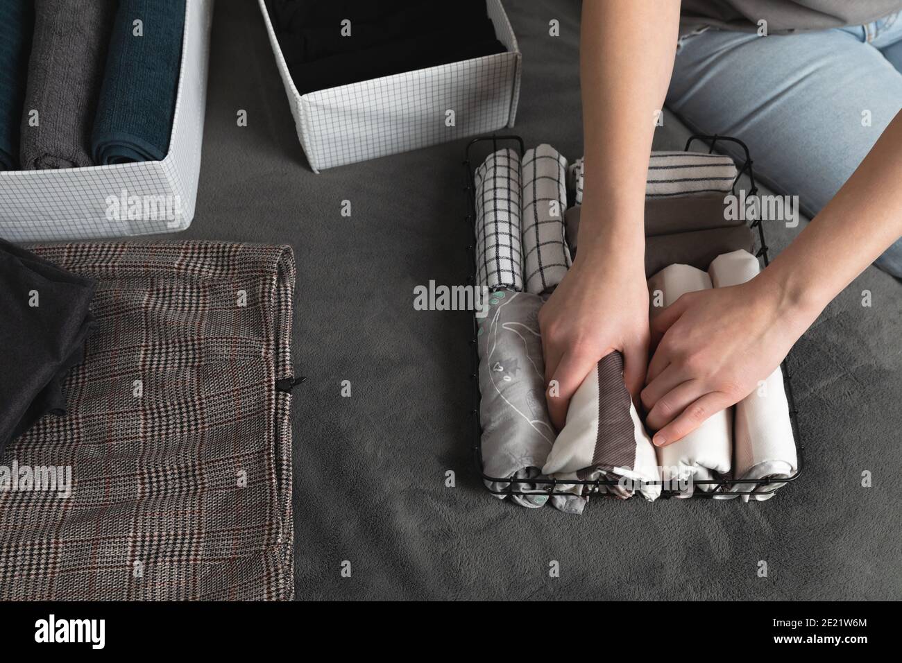 Vertical storage of clothing.Women organize clothes in a modern bedroom