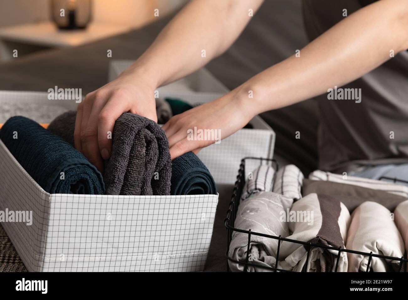 Vertical storage of clothing.Women organize clothes in a modern bedroom. Women sorting clothes in baskets room cleaning concept. Stock Photo