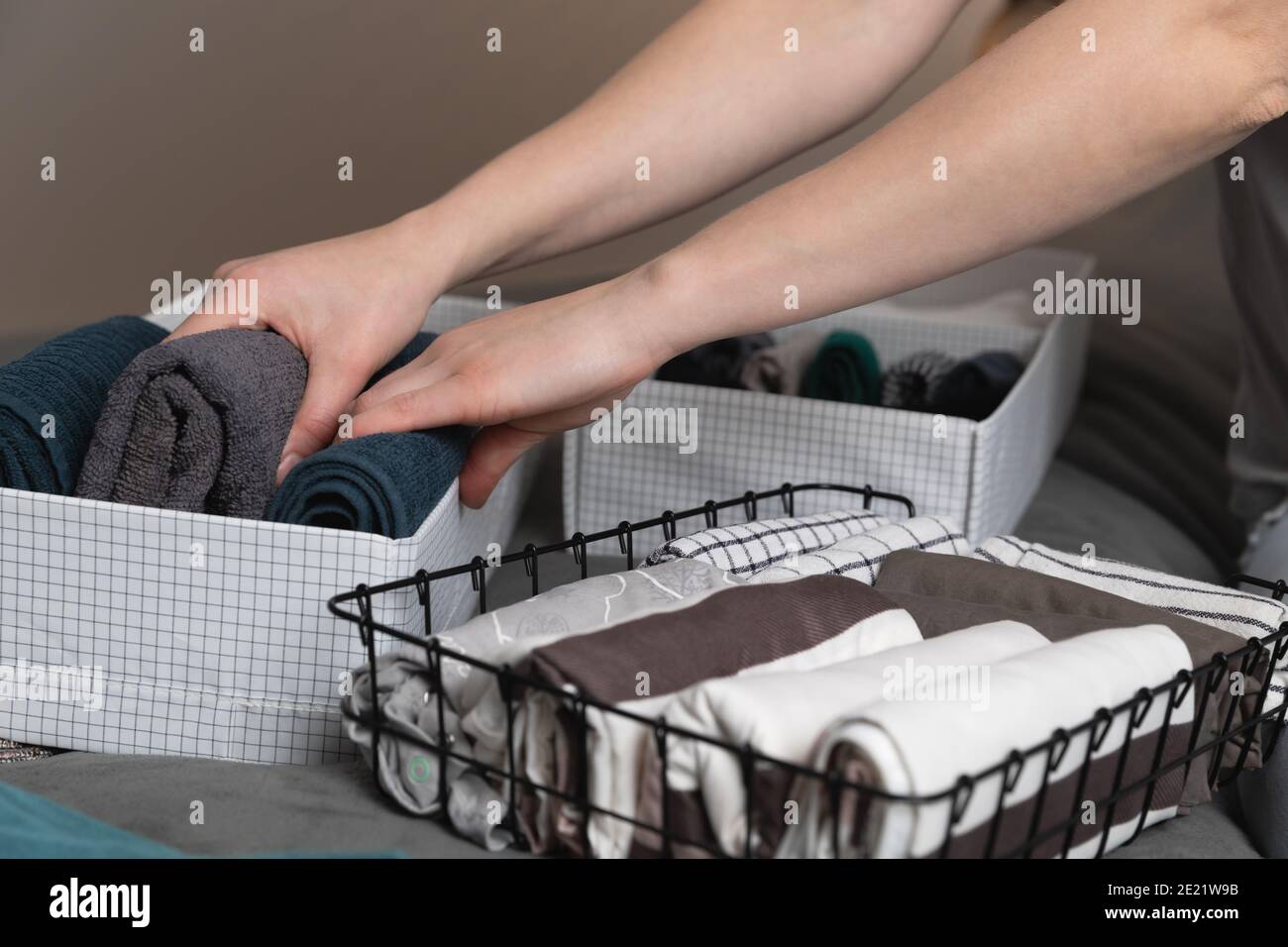 Vertical storage of clothing.Women organize clothes in a modern bedroom