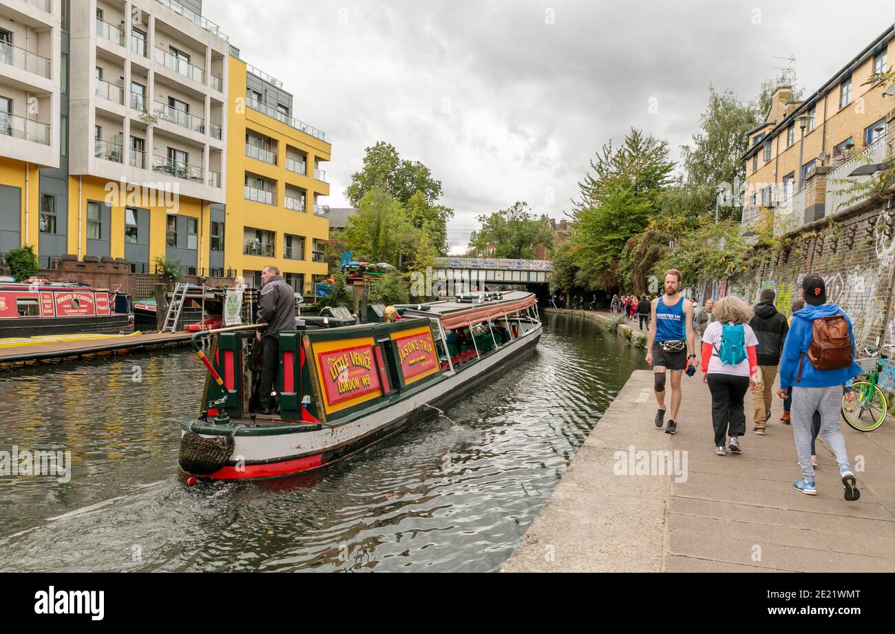 View of Regents Canal in Camden, London, UK, with narrow boat and walkers on the towpath Stock Photo