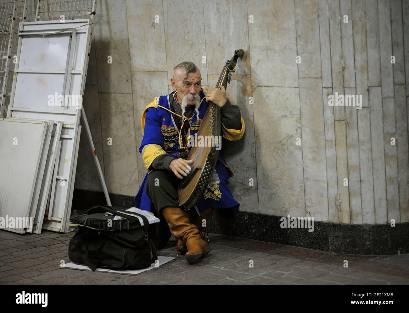 An old man in Ukrainian national clothes, street musician, playing native musical instrument kobza in the empty subway passage. October 30, 2012. Kiev Stock Photo
