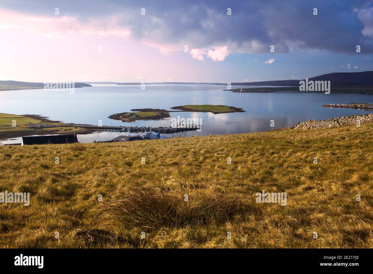 Aerial view from top of hill above Stromness on Orkney islands in Scotland with two small islands in background and golden grass in foreground Stock Photo