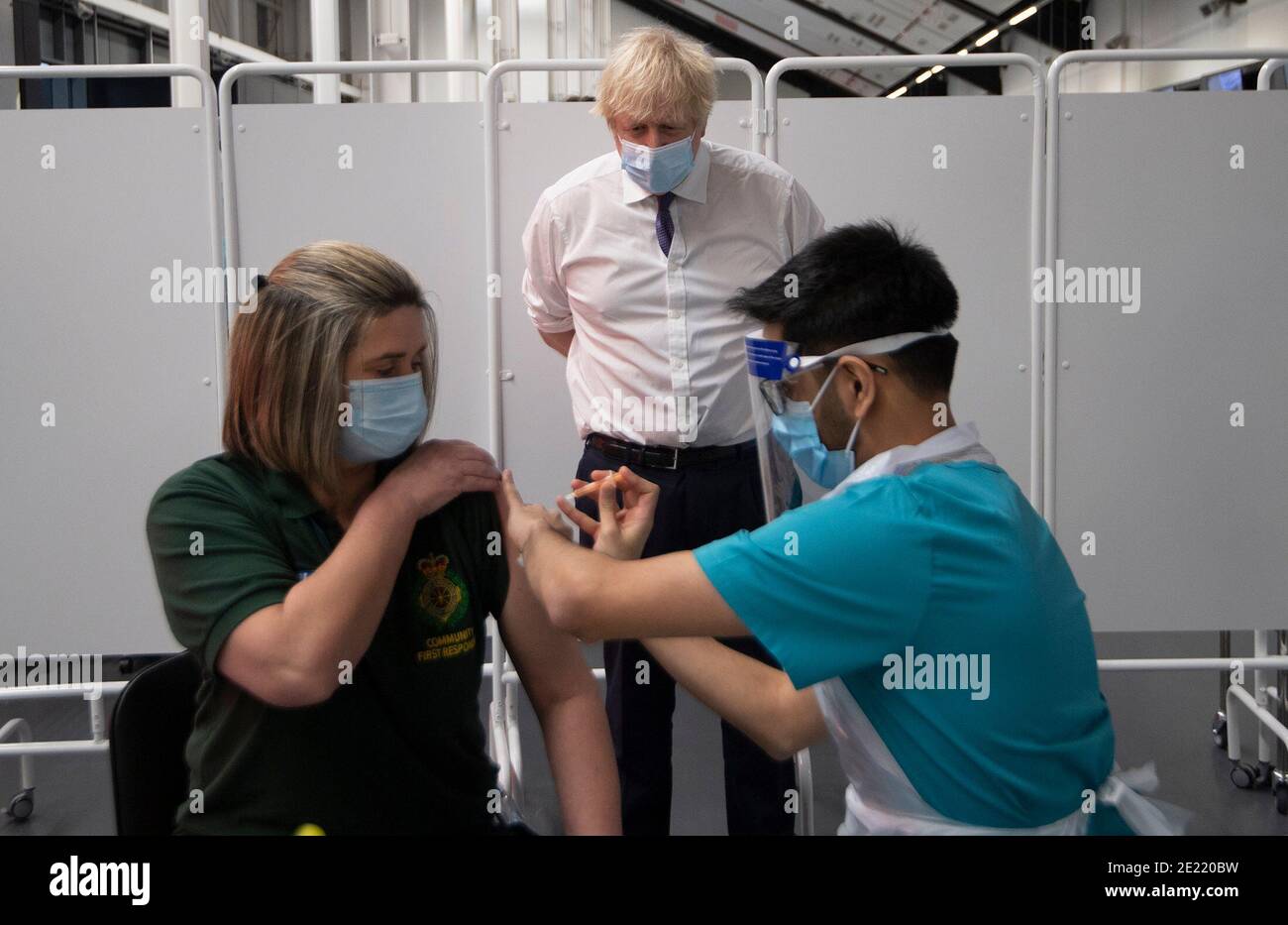 Prime Minister Boris Johnson at Ashton Gate Stadium in Bristol watches first responder Caroline Cook receiving an injection of a Covid-19 vaccine during a visit to one of the seven mass vaccination centres now opened to the general public as the government continues to ramp up the vaccination programme against Covid-19. Stock Photo
