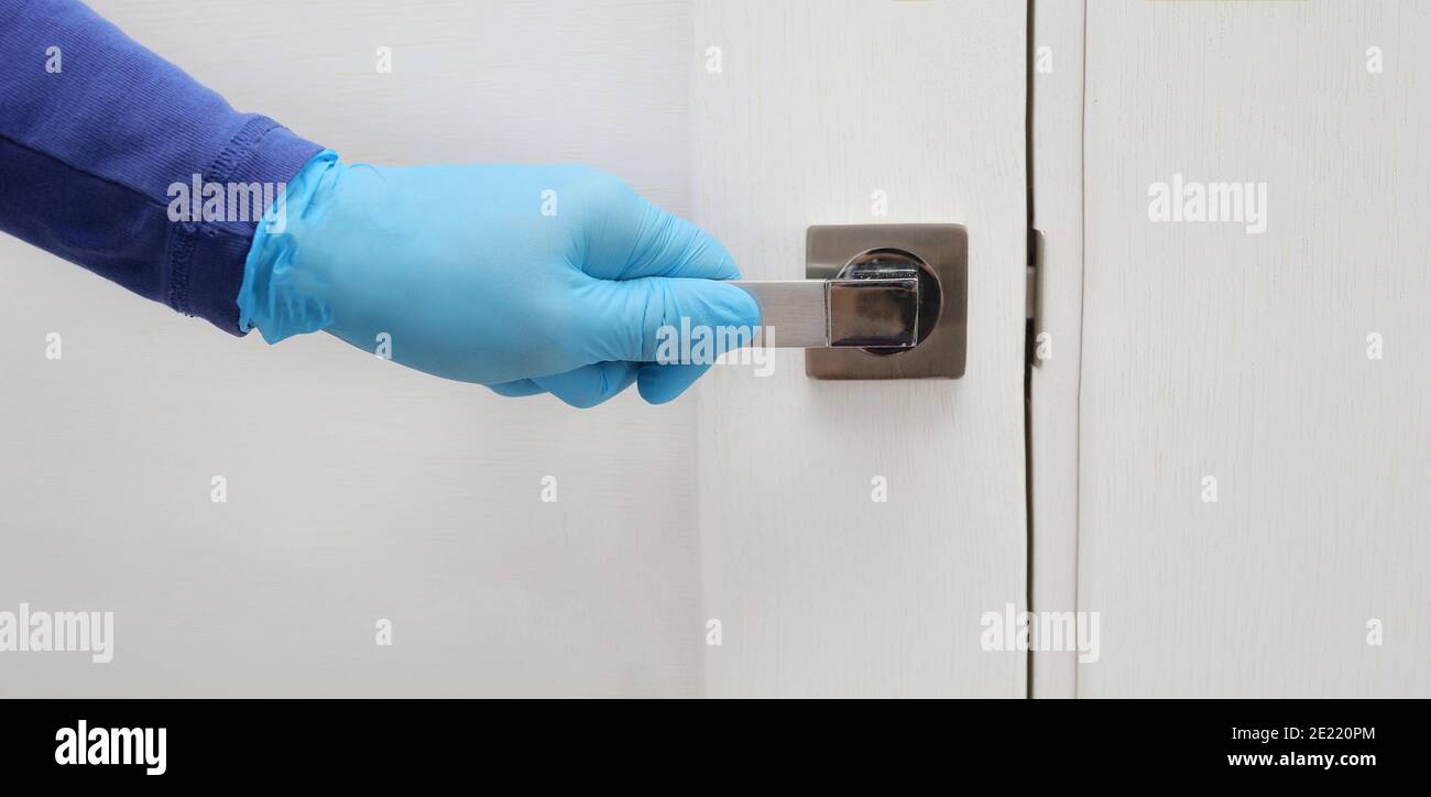 Mens hand in a blue protective gloves opens or close the door. Antibacterial prophylaxis banner in times of viruses and infections. Health and Stock Photo