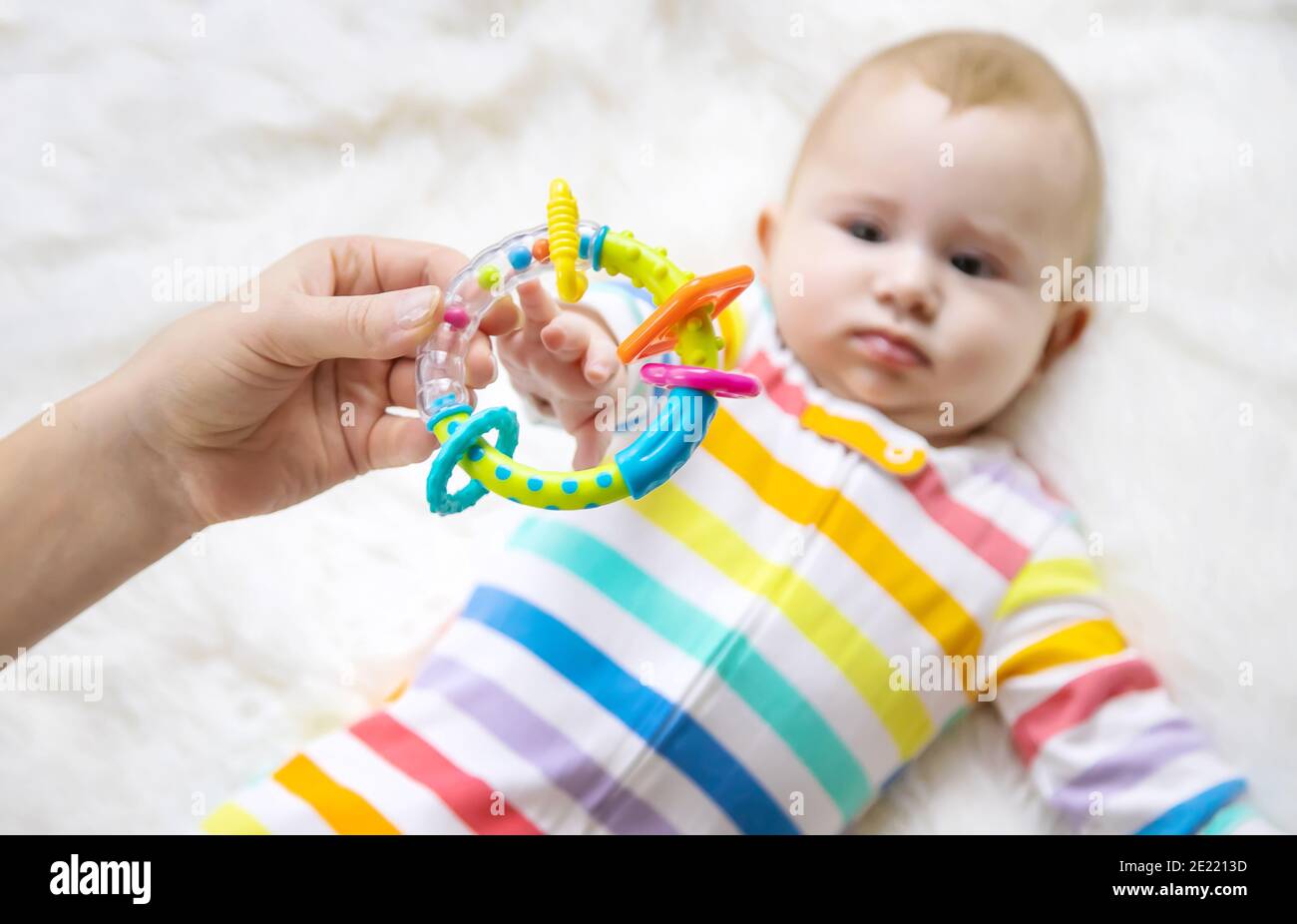 The mother gives a rattle to the baby. Selective focus. child Stock