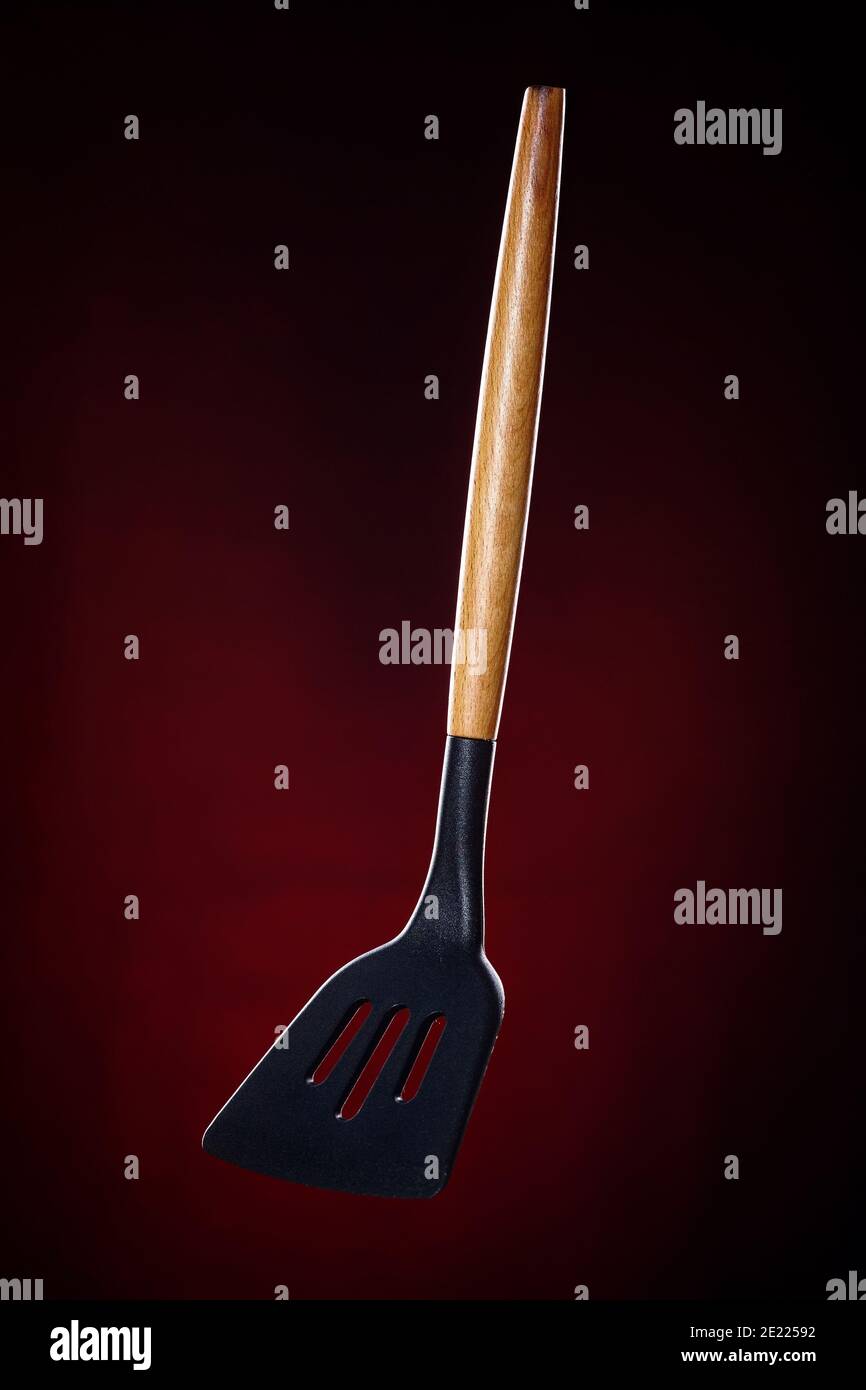 Kitchen spatula for turning meat. This is a promotional photo of kitchen utensils on a dark background. Stock Photo