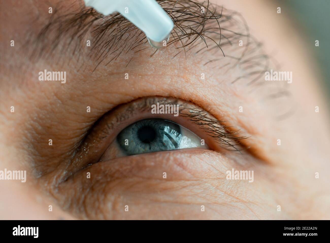 A man puts eye drops in his eyes before putting on contact lenses