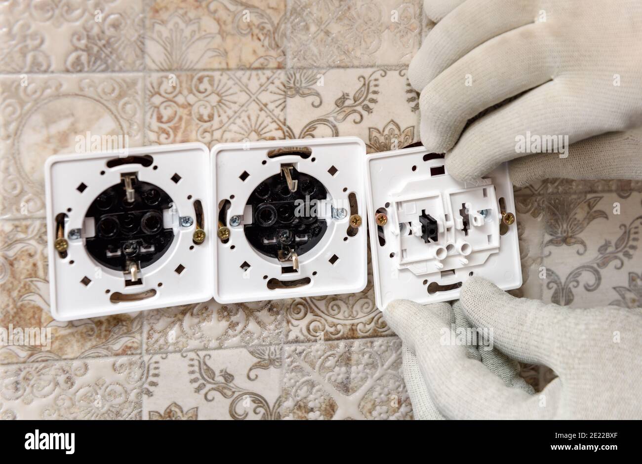 An electrician is installing switches and sockets on the wall. Stock Photo