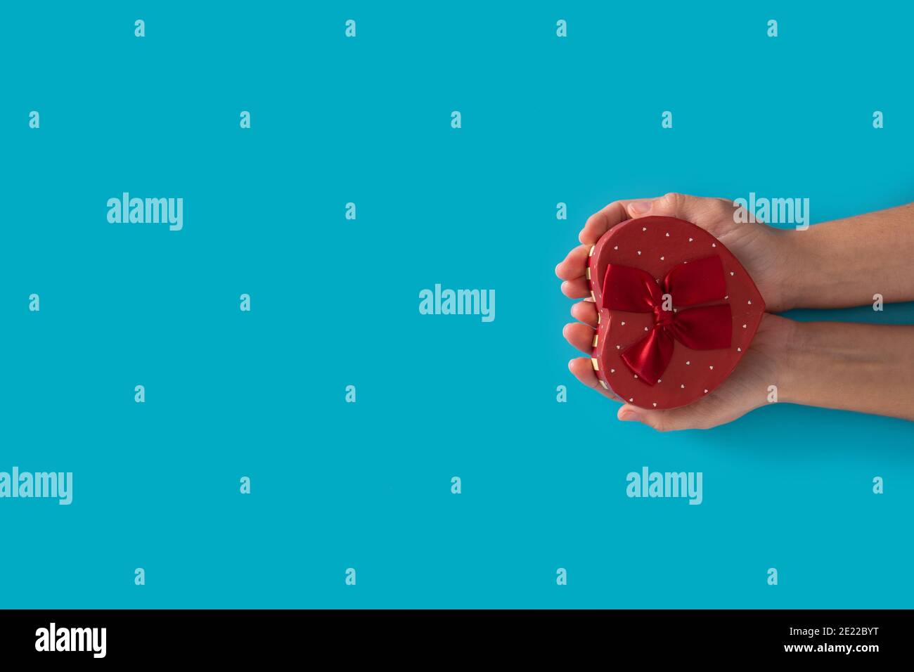Woman hands holding heart shaped box on blue background Stock Photo