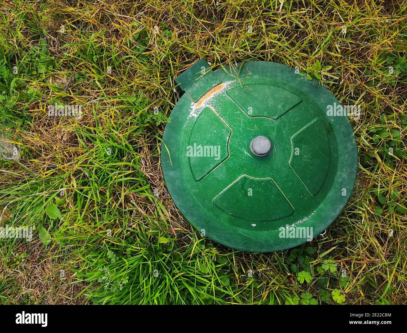 Top view of an underground gas tank cap in a meadow under the sunlight ...