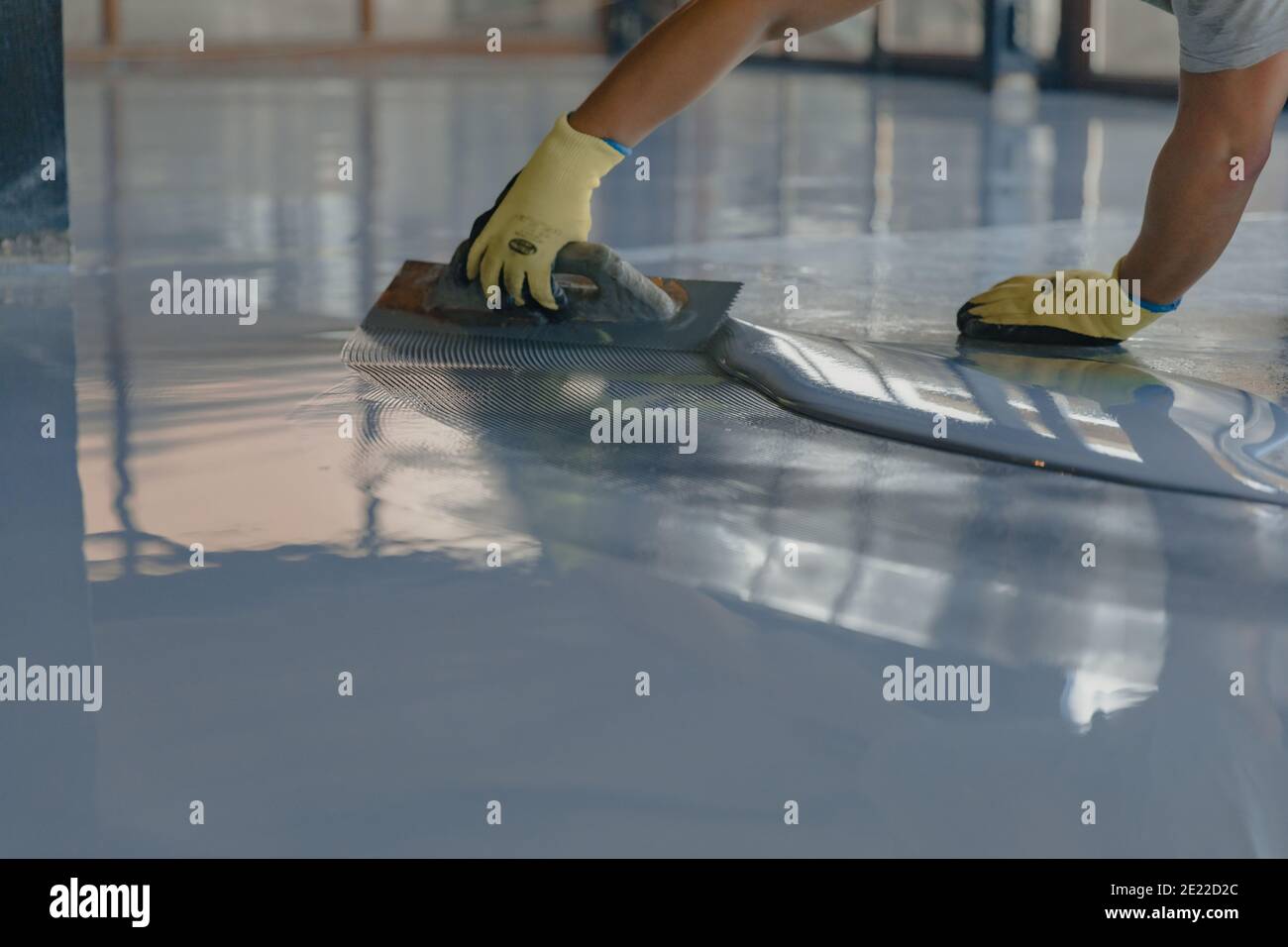 The worker applies gray epoxy resin to the new floor Stock Photo