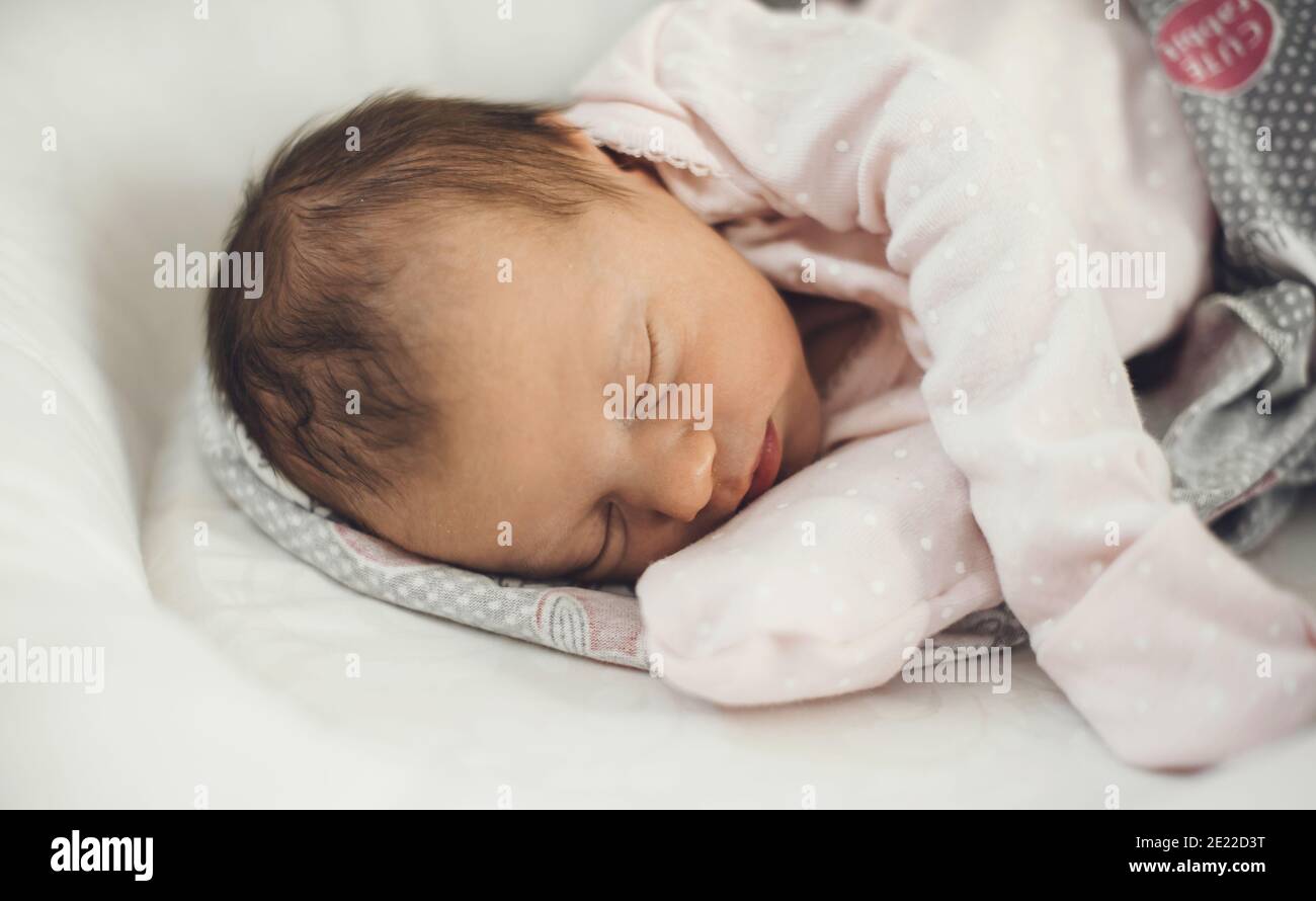 Newborn baby sleeping well while wearing warm clothes and lying on a baby couch Stock Photo Alamy