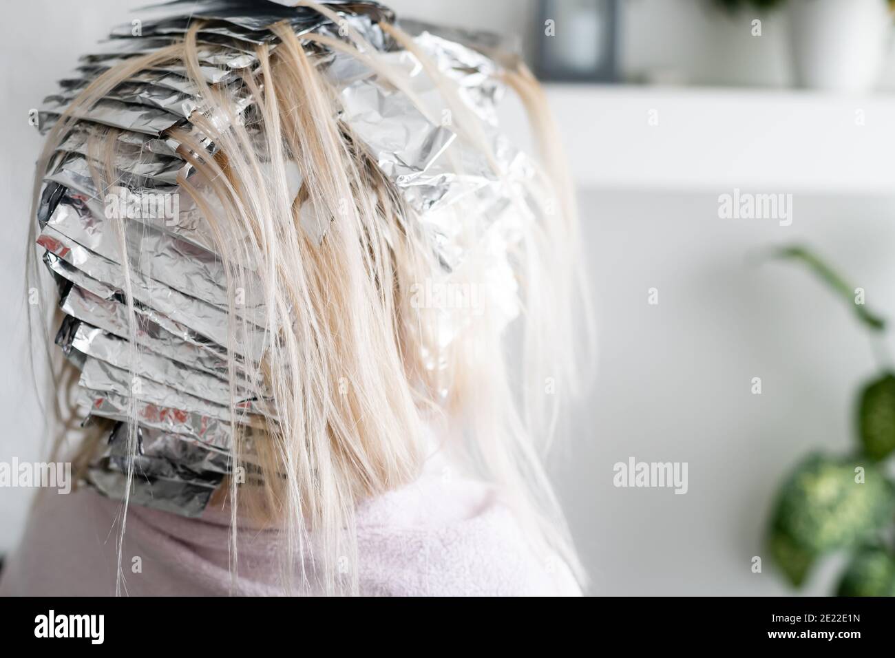Beautiful young woman with foil on her hair. Bleaching or dyeing