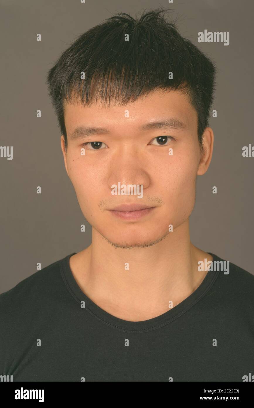 Studio shot of young Chinese man against gray background Stock Photo