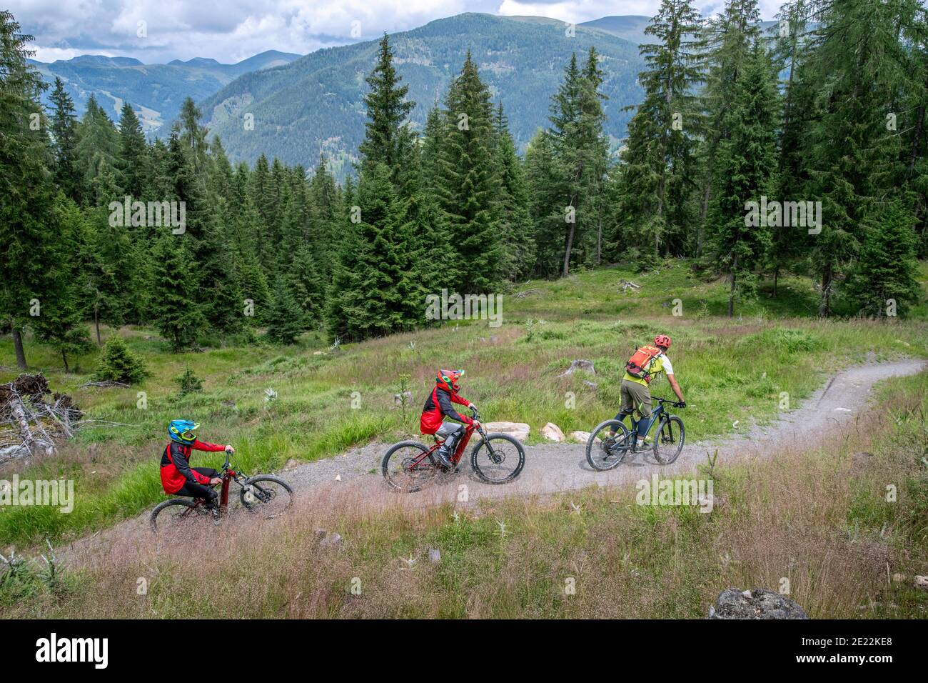 Family of mountain bikers riding their mountain bikes along downhill track through forest in summer, Carinthia / Kärnten, Austria Stock Photo