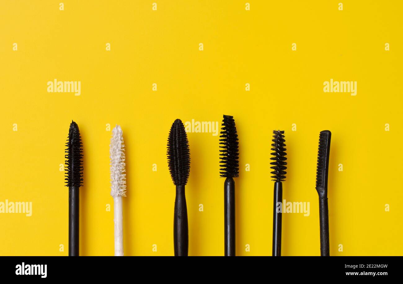 Various types of mascara wands on yellow surface Stock Photo