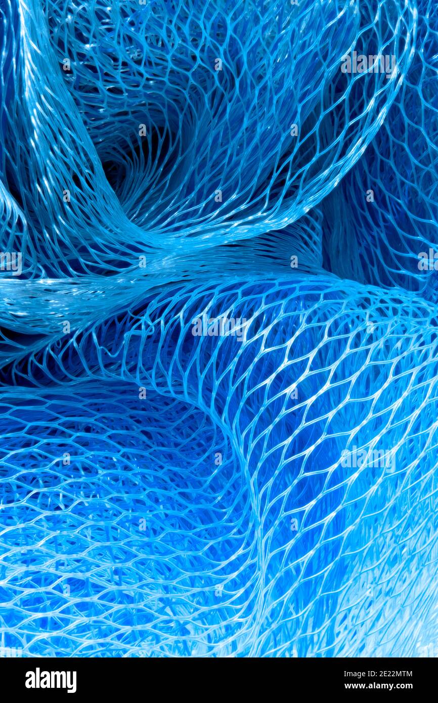 Closeup macro photograph macrophotograph of the patterns in a blue mesh ball used when showering, also called a loofah or scrunchie skrunchie. Stock Photo