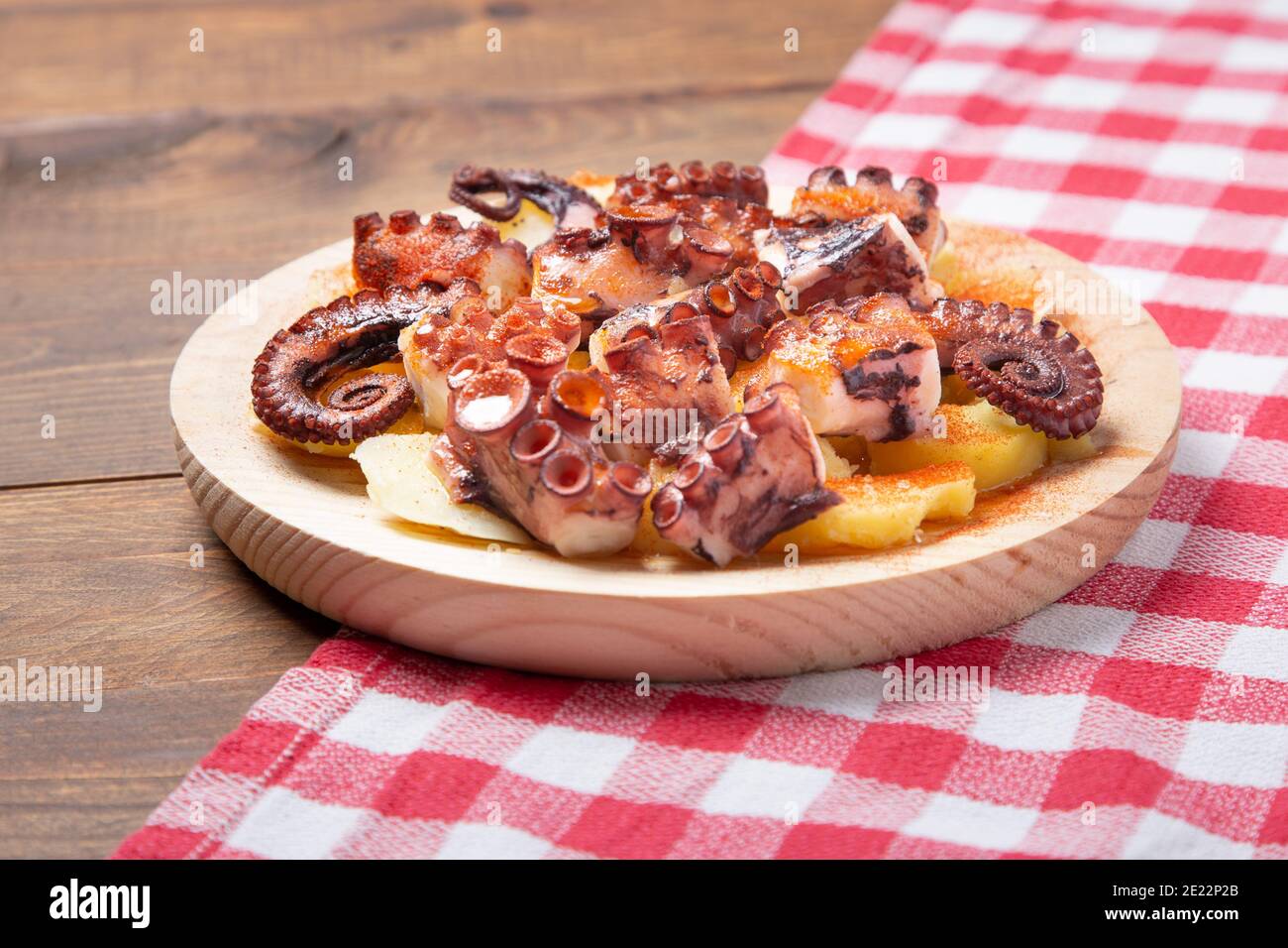 Pulpo a la gallega,galician octopus with ,potatoes paprika, salt and olive oil.  typical Spanish Galician tapa, on a traditional wooden plate. Tipical. Stock Photo