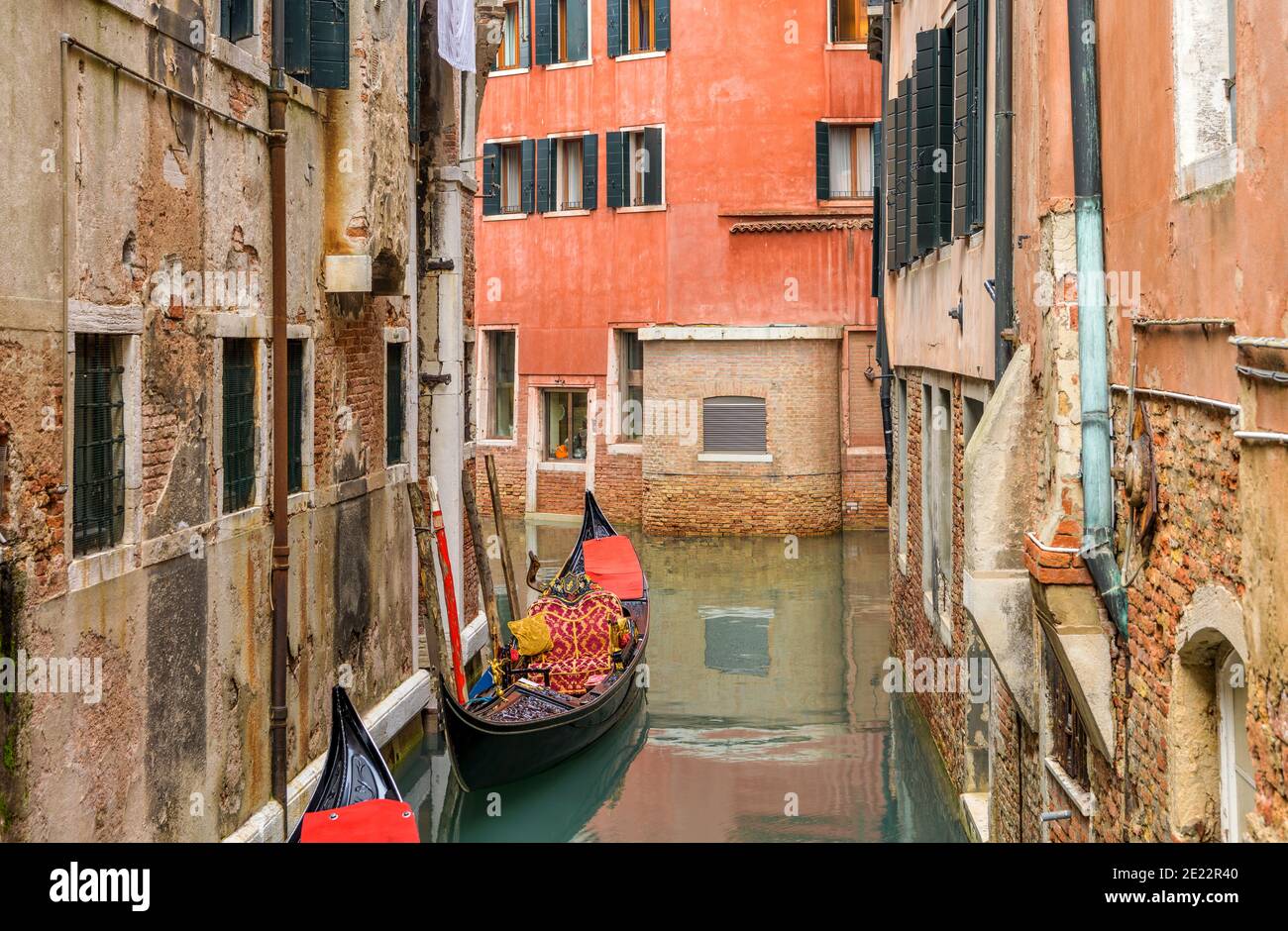 Quiet Water Alleyway - A colorful and decorative Venetian Gondola, a popular tourist rowing boat, idling in a narrow waterway in Venice, Veneto, Italy. Stock Photo