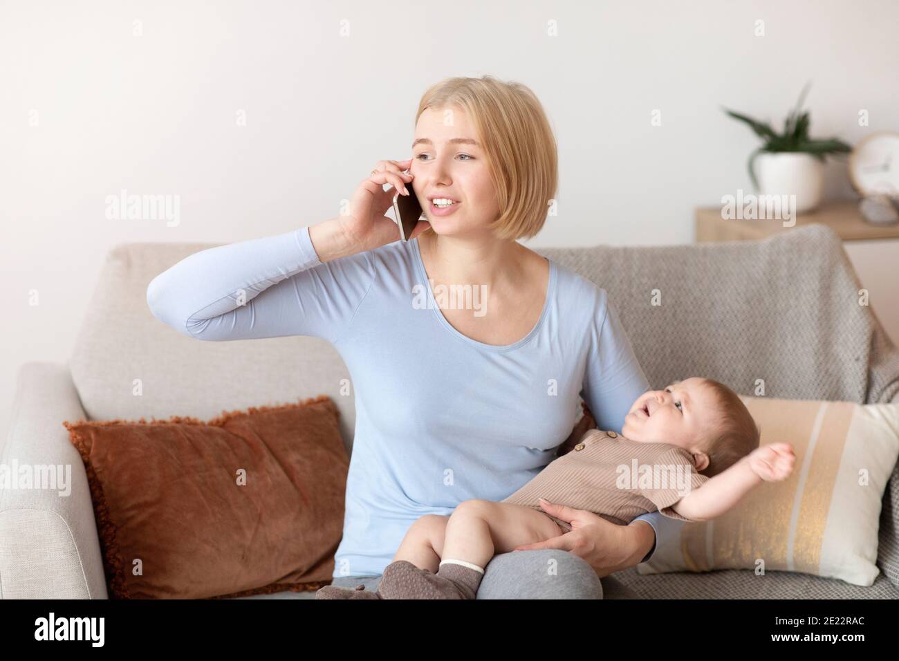 Worried mother with crying sick baby calling pediatrician Stock Photo