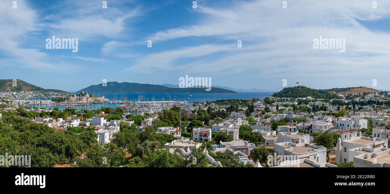 Panoramic distant view at Bodrum town with harbour. Yachts and sail boats anchored in calm waters of Bodrum shallow moon-shaped bay in Turkey. Stock Photo