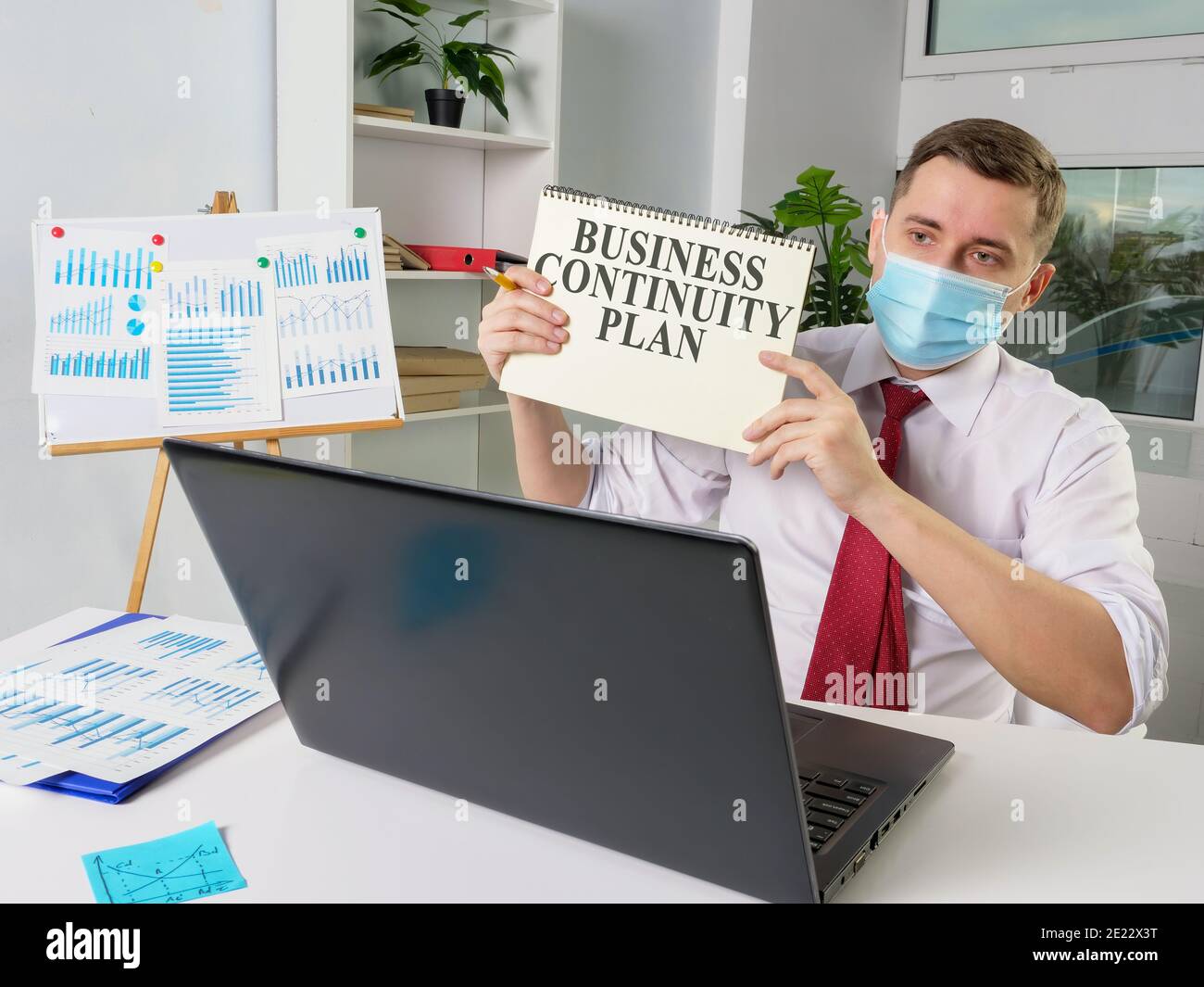 Man in face mask shows Business continuity plan while online meeting. Stock Photo