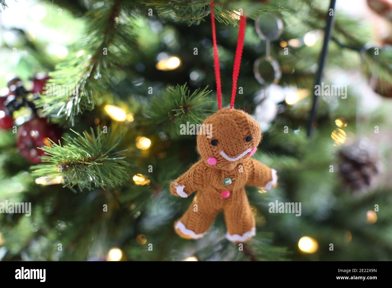 A knitted happy/ smiling gingerbread man/ woman/ person bauble/ Christmas tree decoration hanging on a Xmas tree Stock Photo