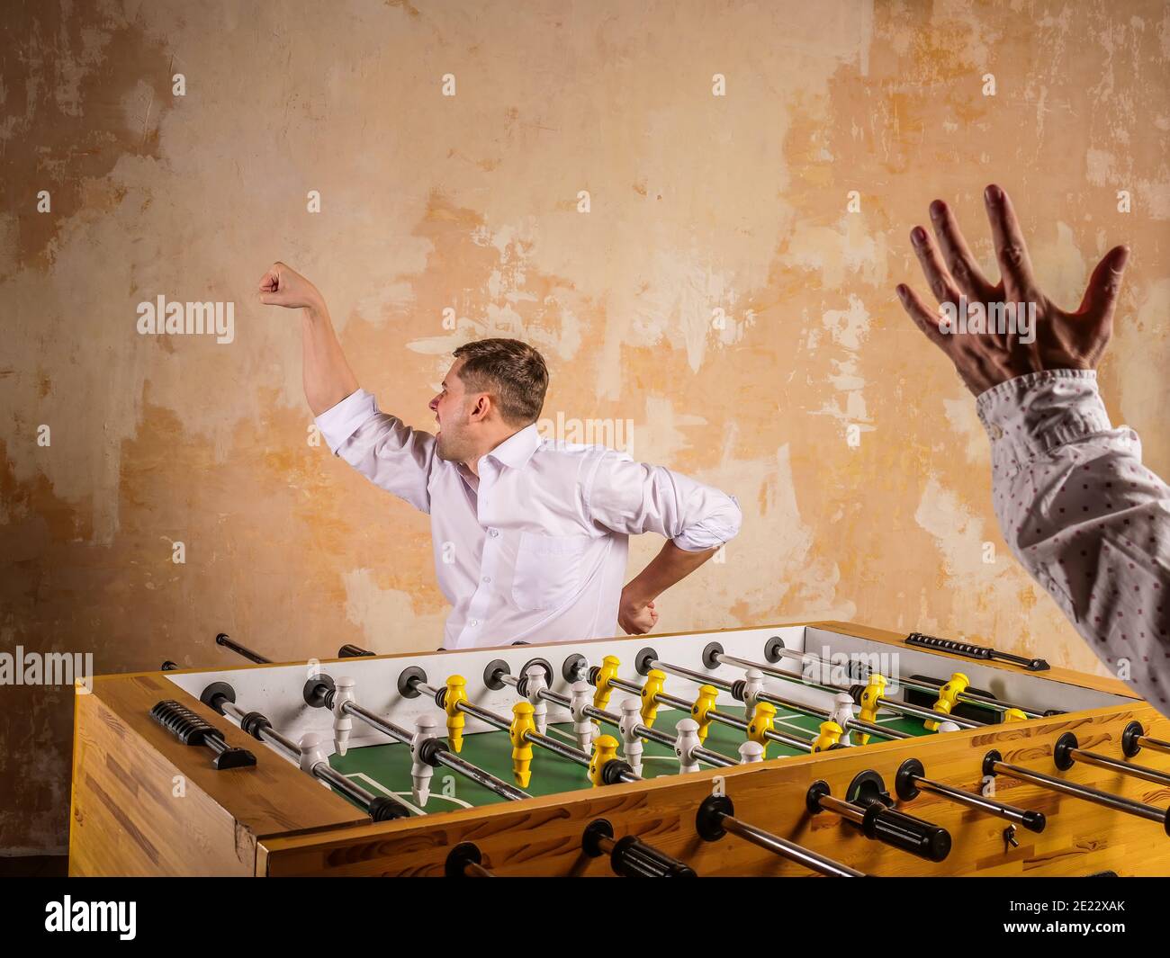 A young man celebrates a victory in table football. Evening active rest. Stock Photo