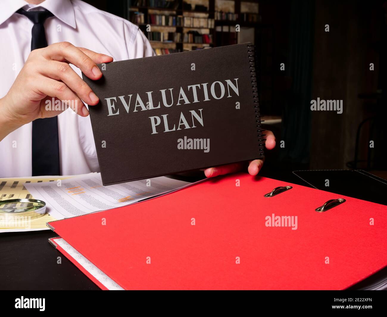 Evaluation plan is in the hands of the clerk who sits at the table. Stock Photo