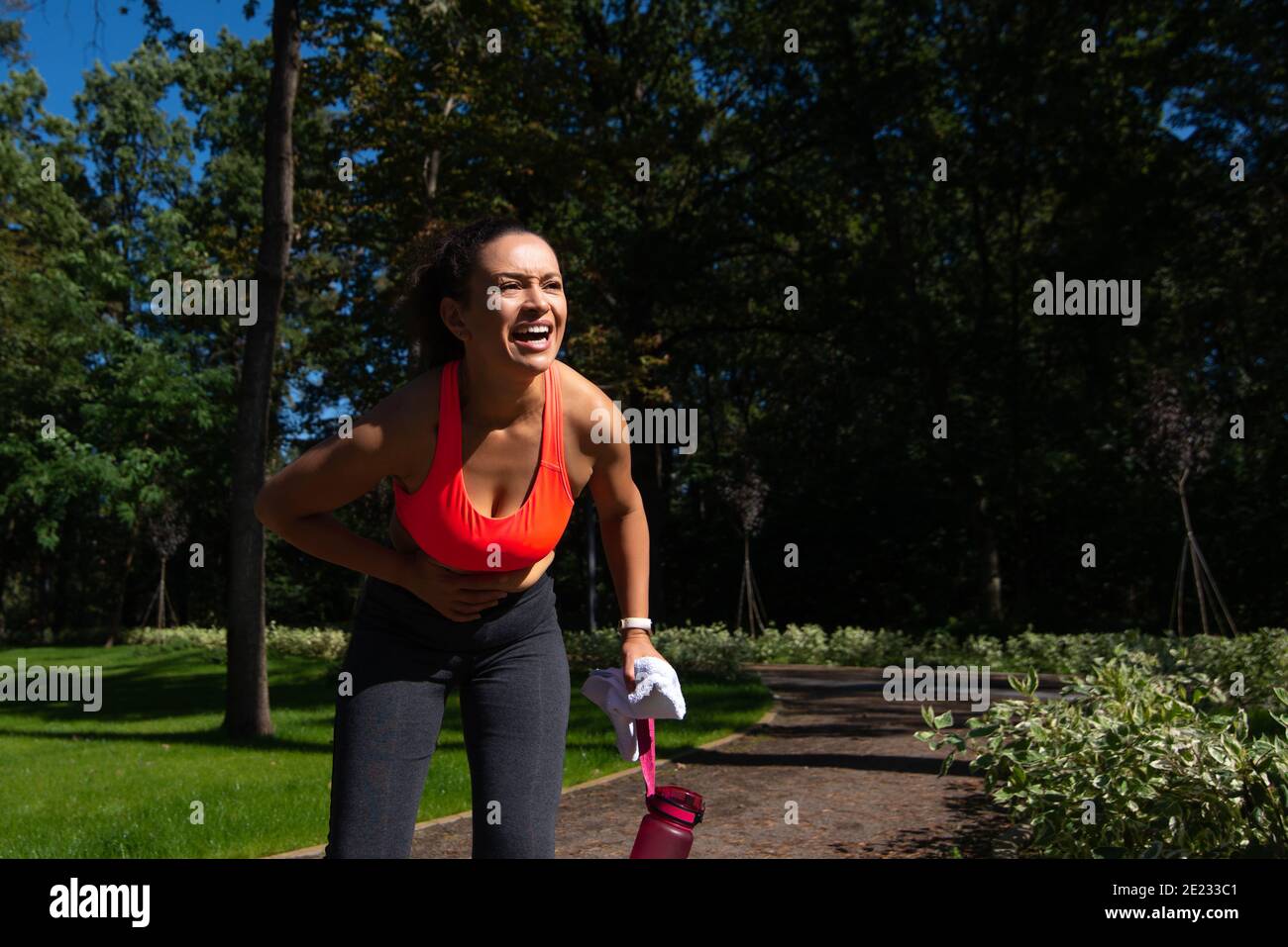 Runner woman feelling abdominal pain after jogging outdoor Stock Photo
