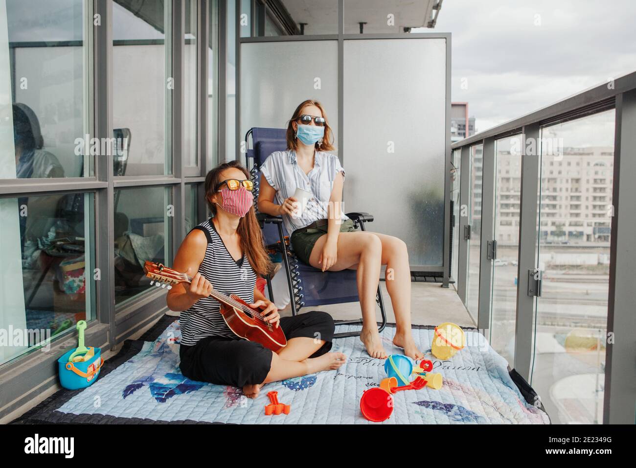 Young lesbian lgbtq women family spending time together on balcony at home. Staycation during coronavirus covid-19 pandemic in the world. Stock Photo
