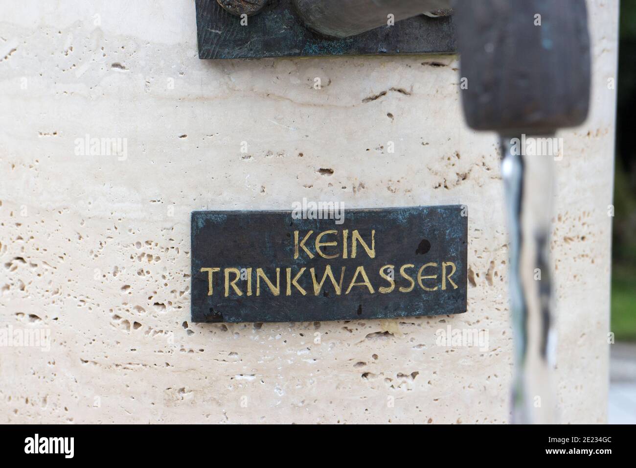 Small metal warning sign by a well with the German text 'Kein Trinkwasser' which translates into 'No drinking water' in English language Stock Photo