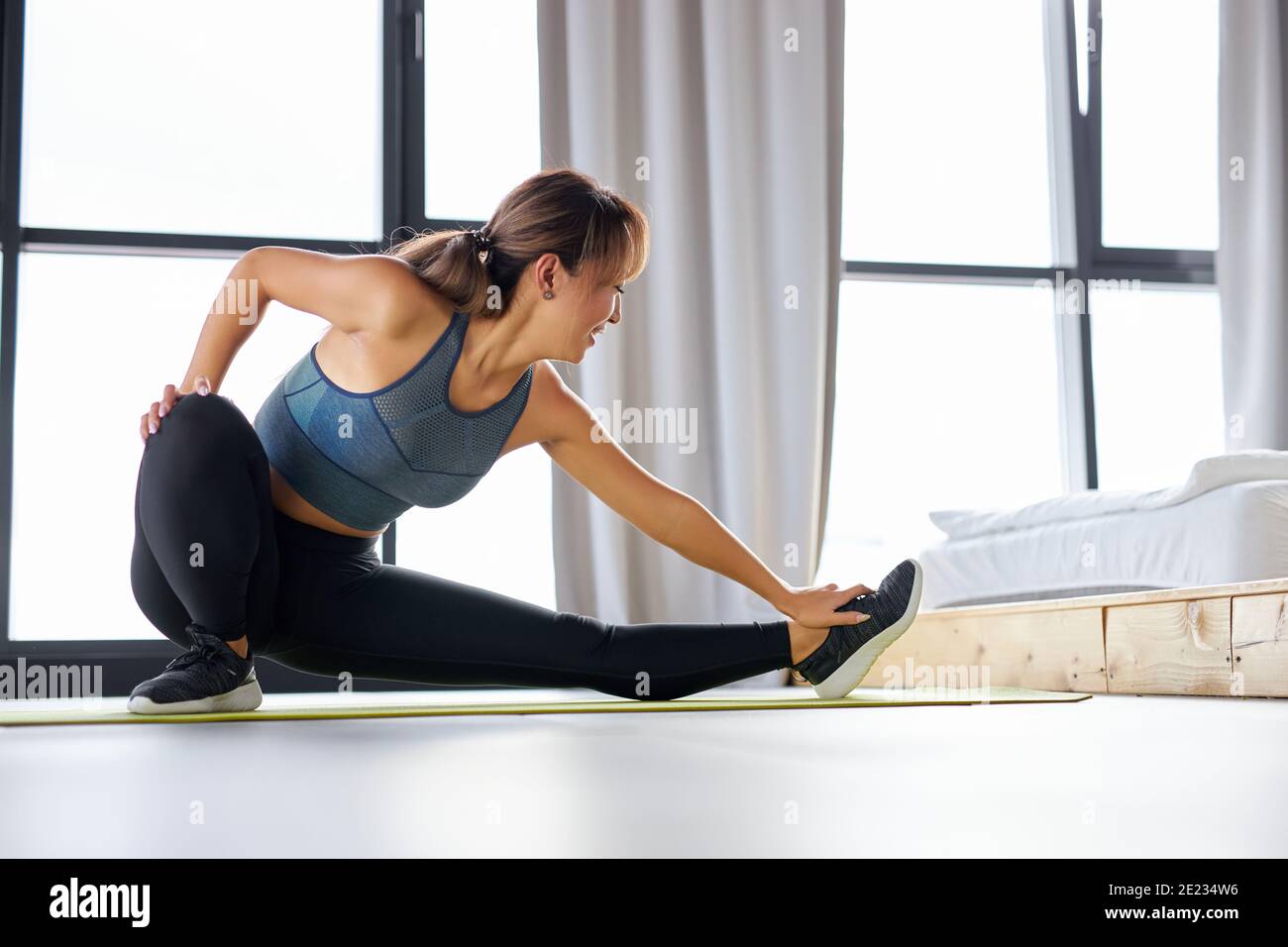 fit woman stretching legs muscles doing sports flexibility exercises at home wearing sportswear. female leads healthy lifestyle Stock Photo Alamy