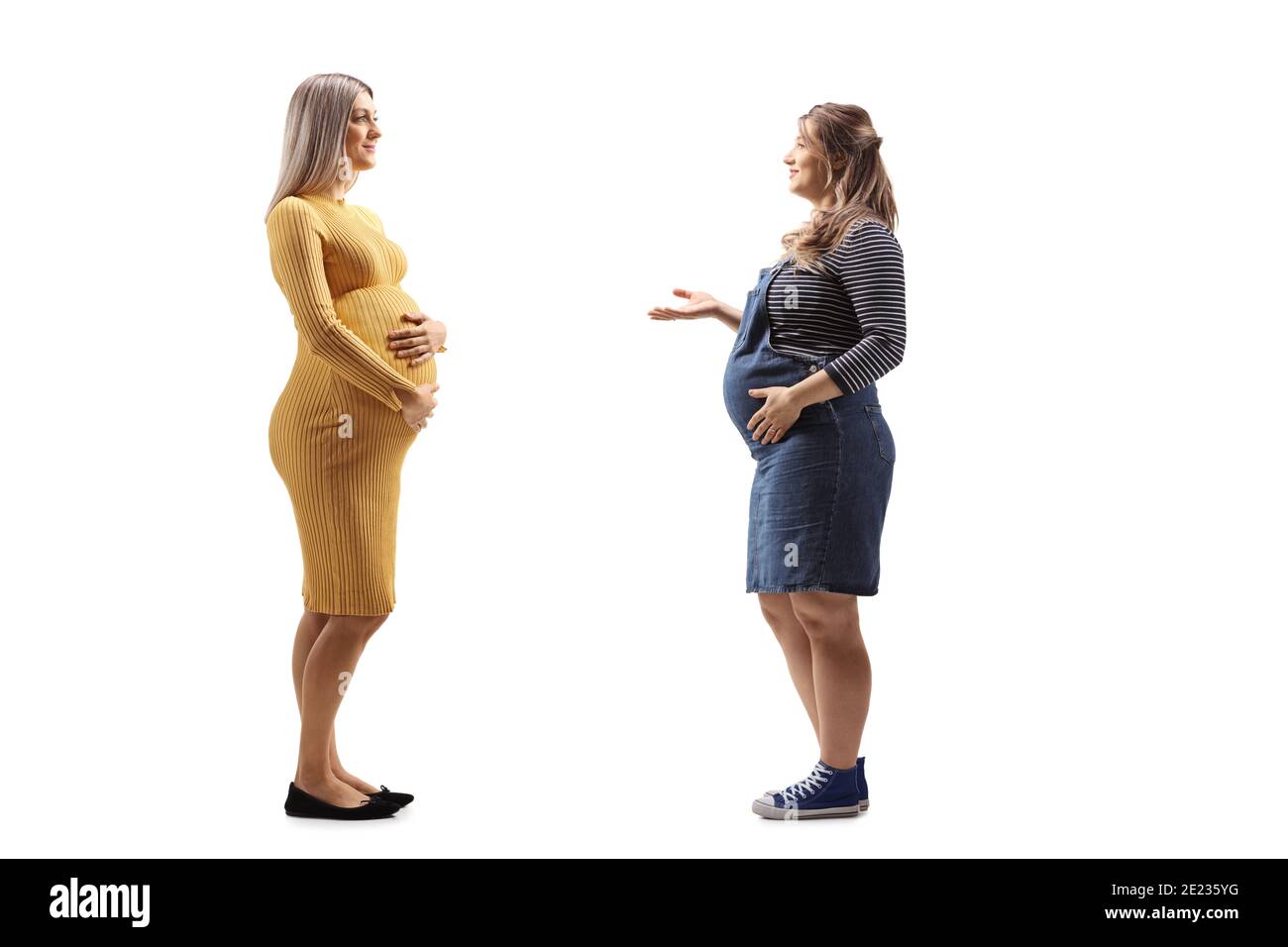 Pregnant woman in a yellow dress having a conversation with another pregnant woman isolated on white background Stock Photo