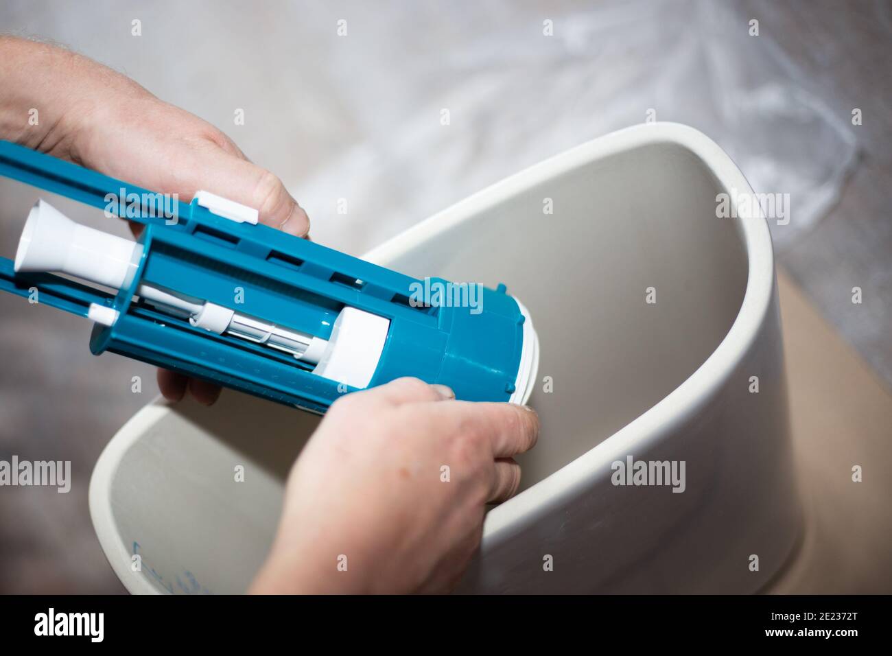 Assembling the toilet. A worker installs a water pump in a ceramic tank