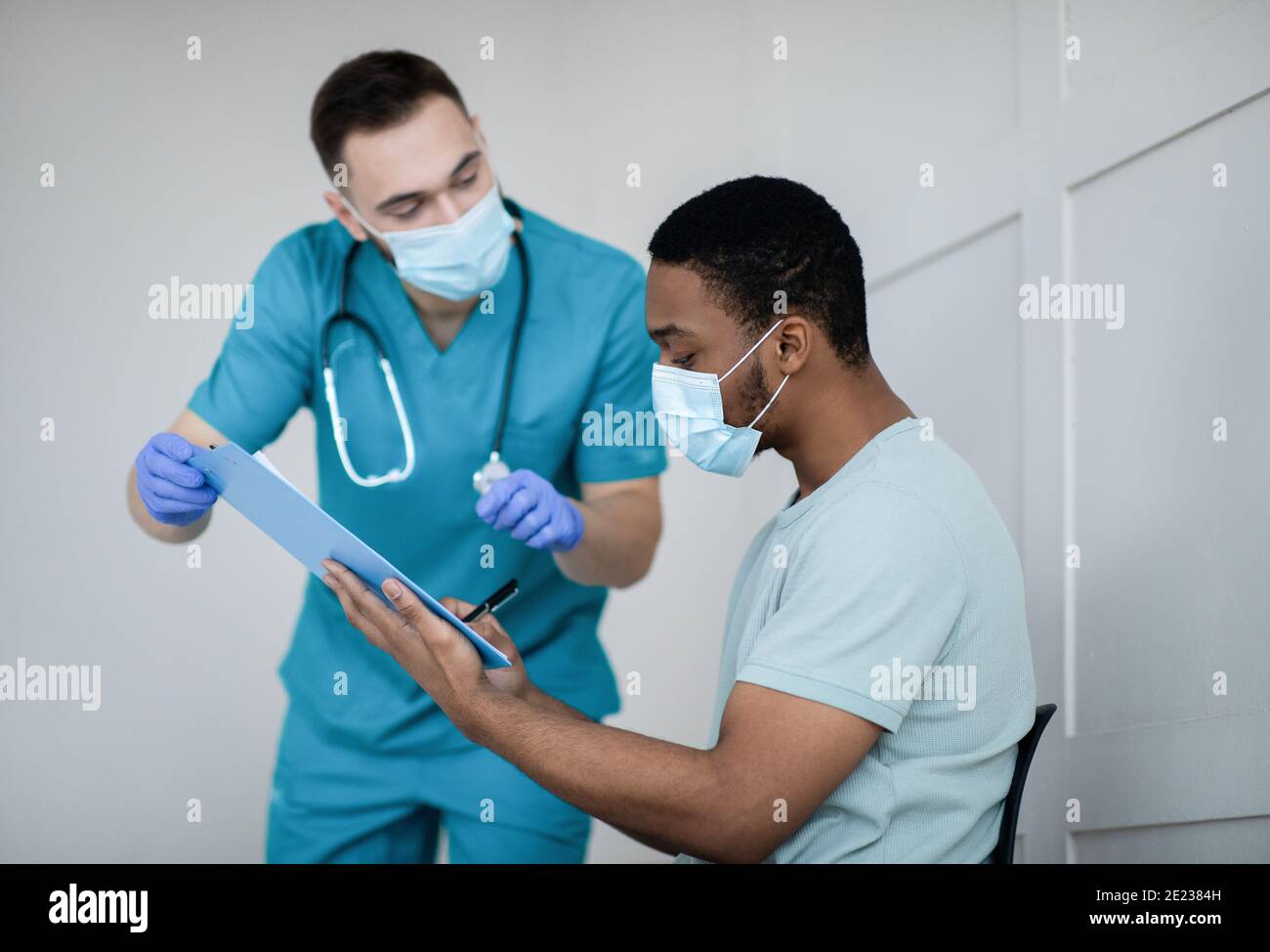 African American male patient signing papers before coronavirus vaccine ...