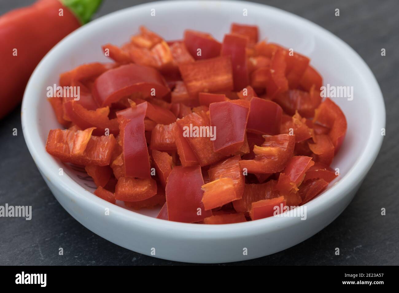 a little white bowl with red hot chili cut in pieces, focus on foreground Stock Photo