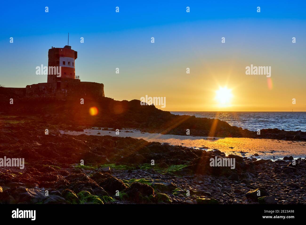 Image of Archirondel beach at low tide with the Jersey Tower shore at sunrise with a clear sky, Jersey Channel Islands Stock Photo