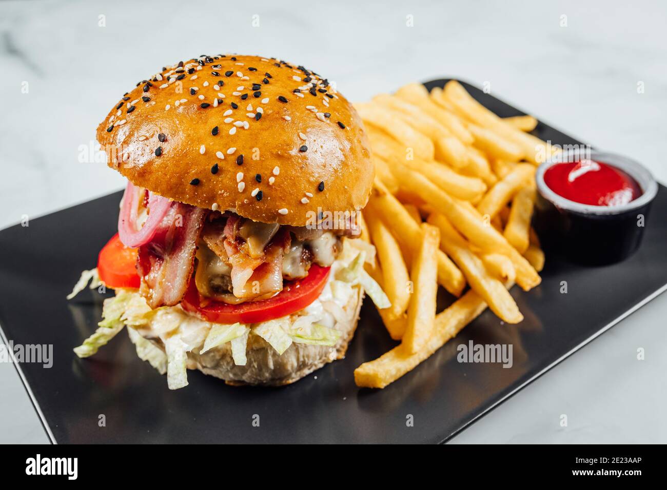 High angle shot of a plate of french fries and a burger on a table ...