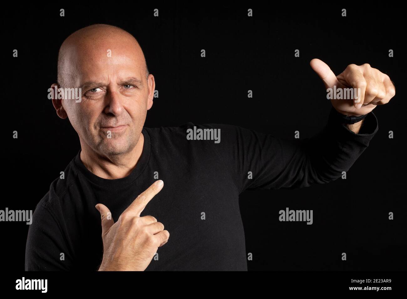 Closeup portrait of a middle-aged bald man with light eyes posing on a black background Stock Photo