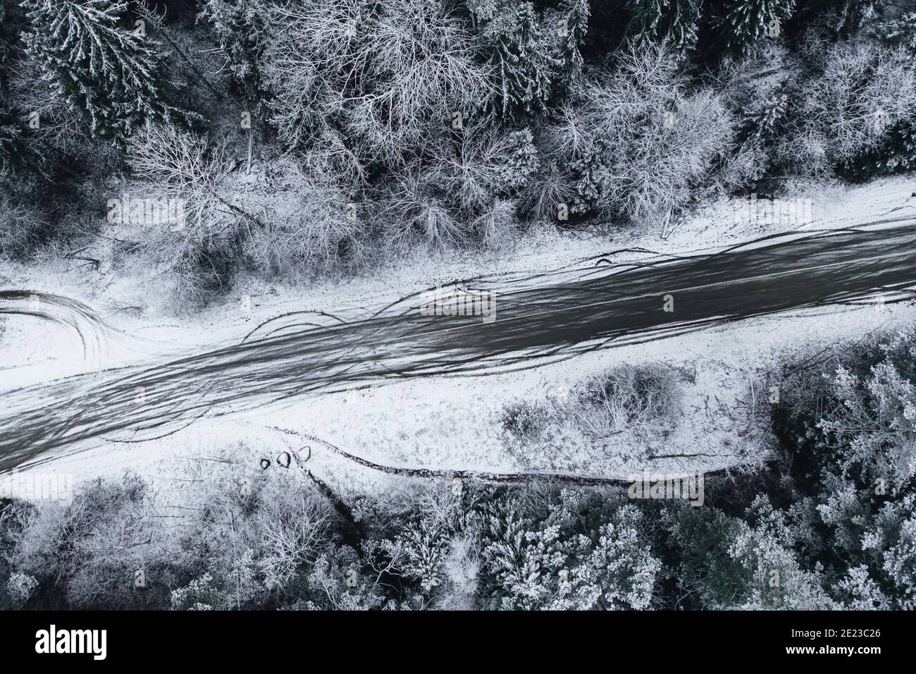 Aerial shot of a road surrounded by beautiful snow-covered forests ...