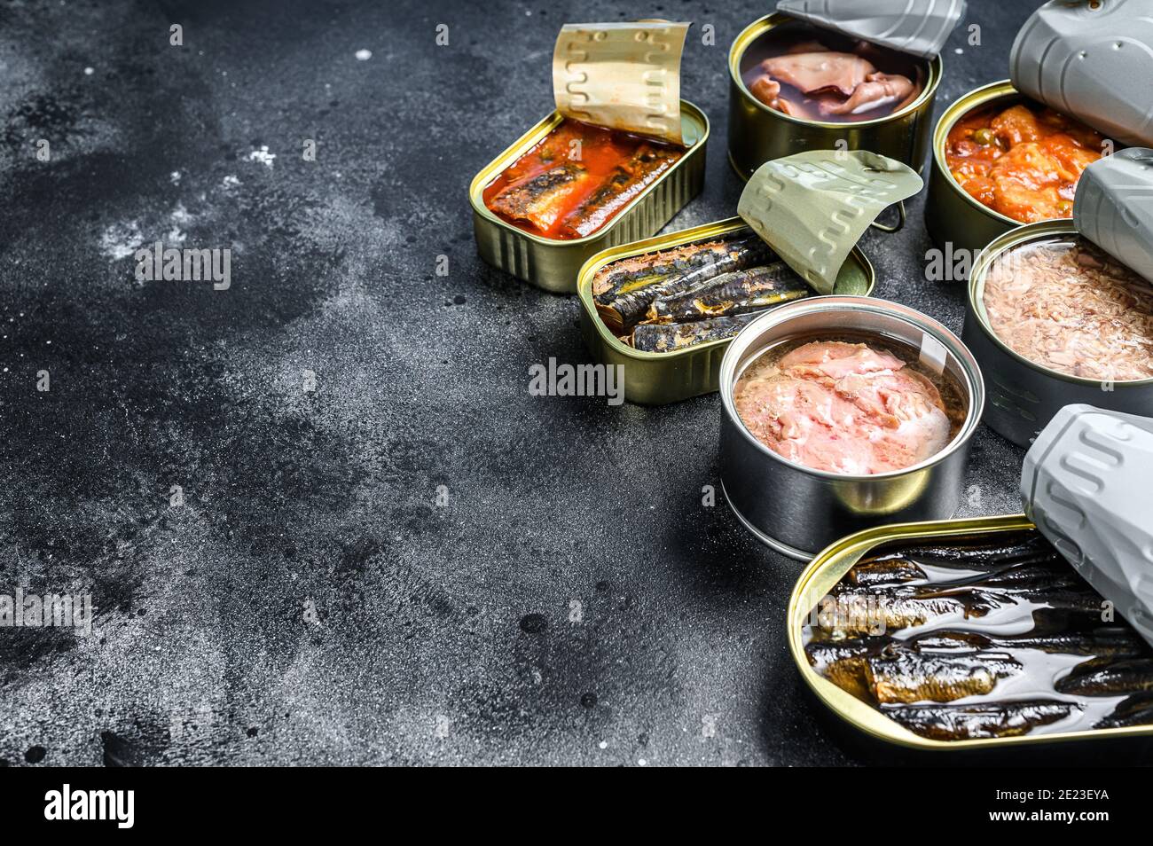 Assortment of cans, canned with different types of fish and seafood. Black background. Top view