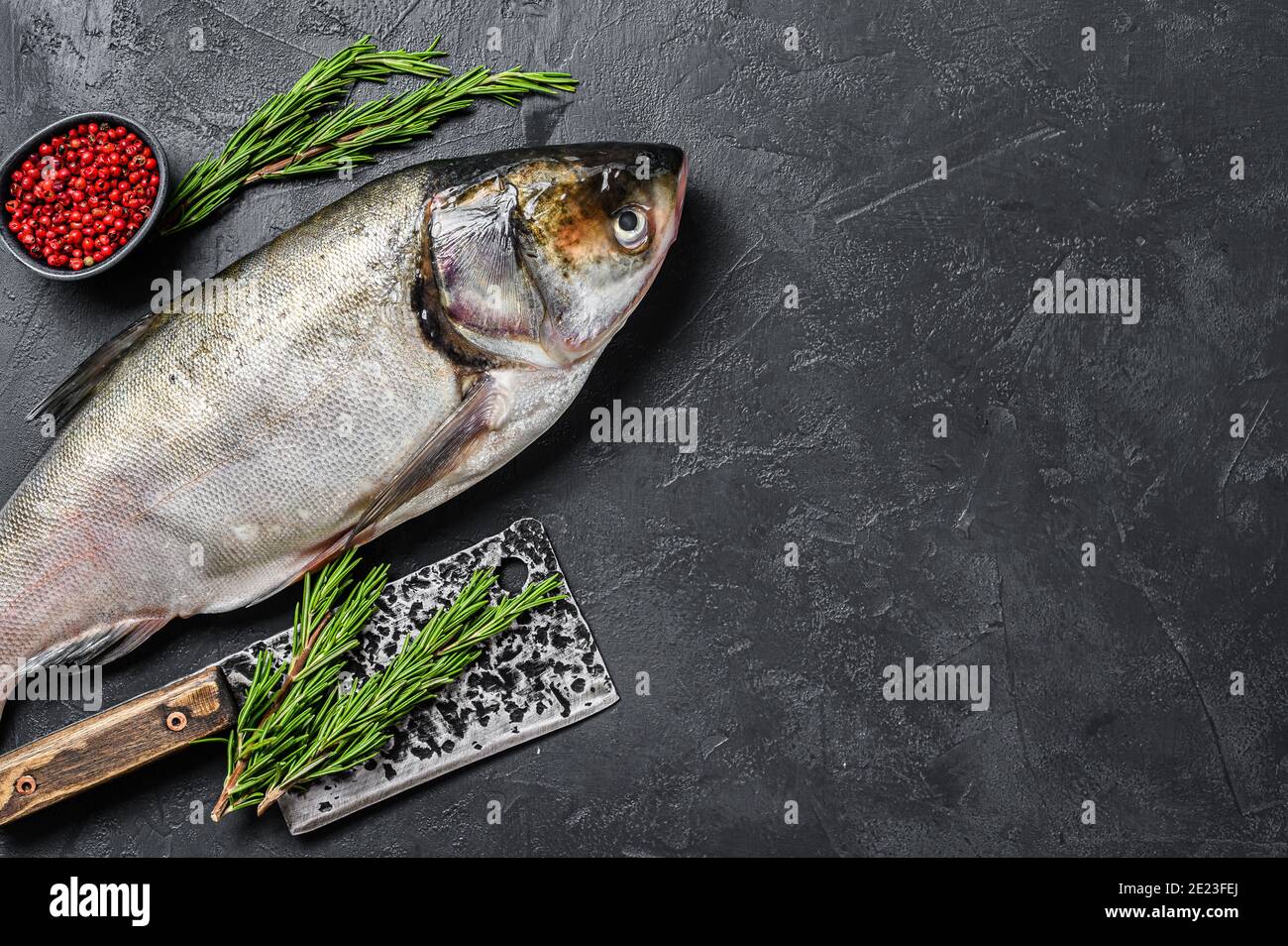 Raw whole fish silver carp with pink pepper and rosemary. Black ...