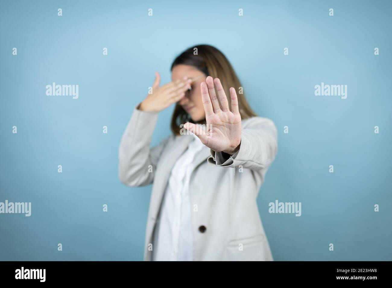 Young business woman over isolated blue background covering eyes with hands and doing stop gesture with sad and fear expression. Embarrassed and negat Stock Photo