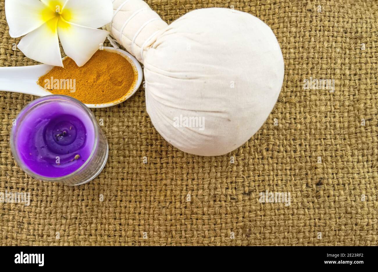 Spa herbal compressing ball , white frangipani flowers (Plumeria spp , Apocynaceae, Pagoda tree, Temple tree) , turmeric powder in wooden spoon and ca Stock Photo