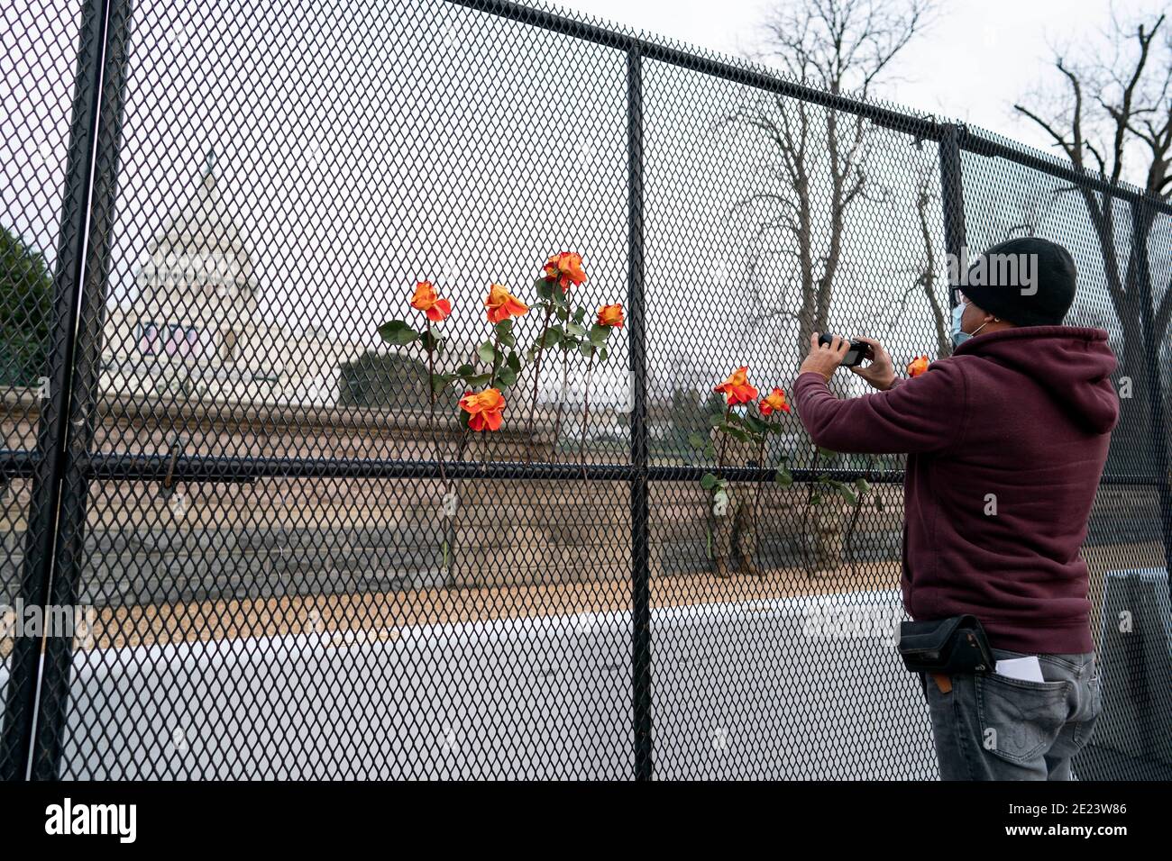 Washington, USA. 12th Jan, 2021. A man takes photos of the U.S. Capitol Building across a barrier fence in Washington, DC, the United States, Jan. 11, 2021. TO GO WITH 'U.S. House Democrats unveil article of impeachment against Trump'. Credit: Liu Jie/Xinhua/Alamy Live News Stock Photo