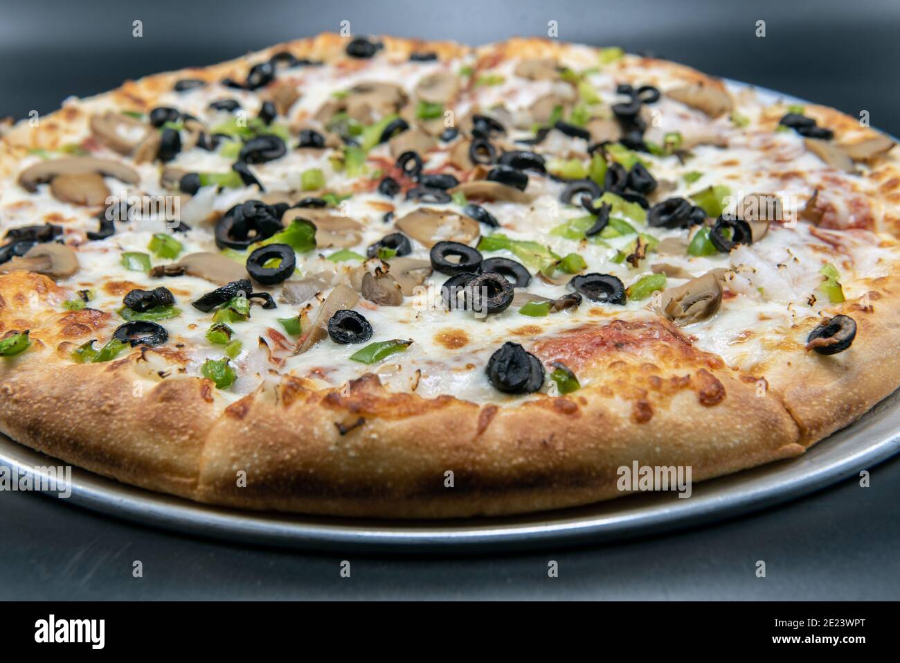 Veggie vegetable covered pizza with melted cheese tempting for those avoiding meat. Stock Photo