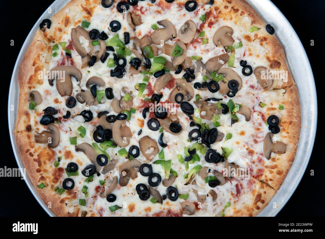 Overhead view of veggie vegetable covered pizza with melted cheese tempting for those avoiding meat. Stock Photo